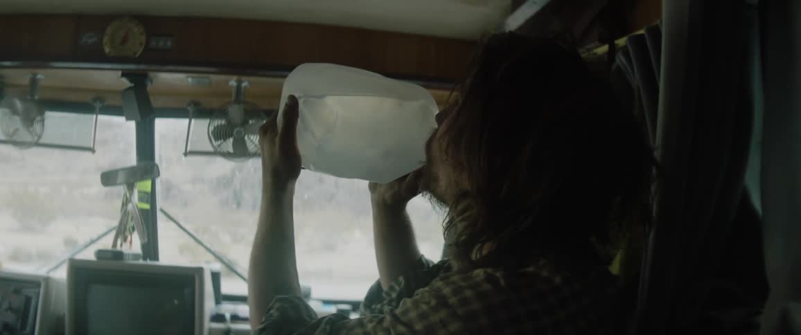 A man camping takes a big drink of water out of a gallon jug