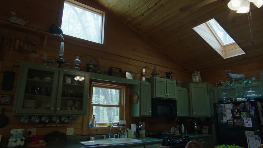 Light shines in from windows in a large kitchen with many cupboards