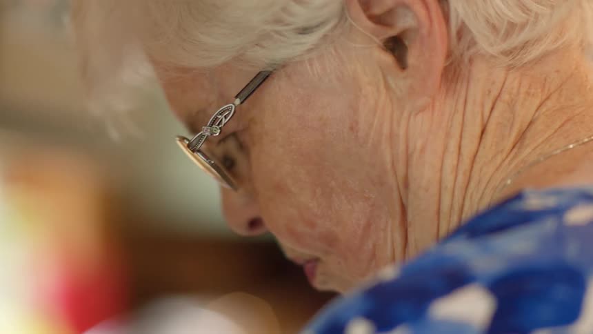 An elderly woman in glasses with wrinkles and white hair