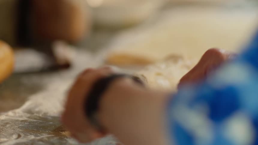 A woman uses thread to slice uncooked cinnamon rolls from a log of dough