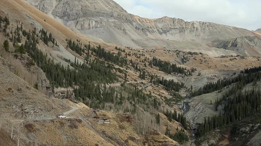 An suv travelling along a winding dirt road in the mountains