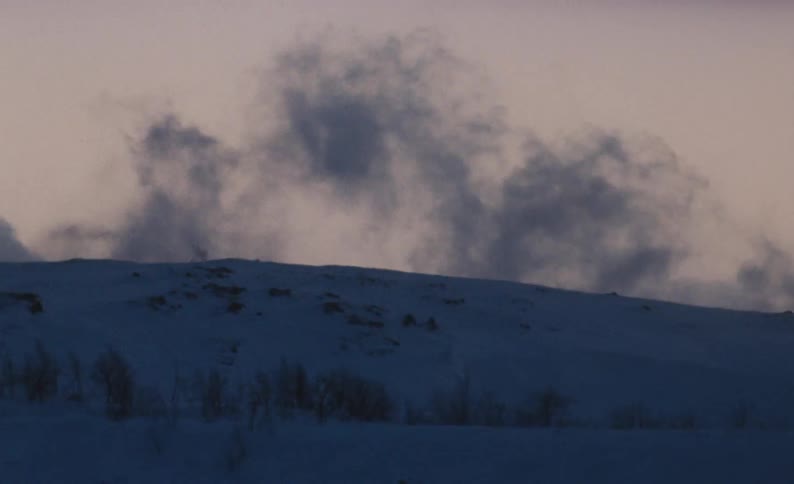 Snow blows over a snowy hill