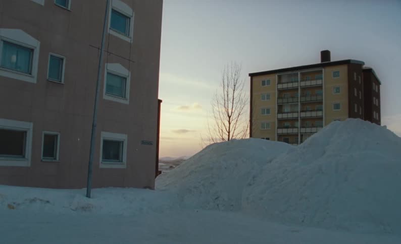Big piles of snow next to an apartment building in winter