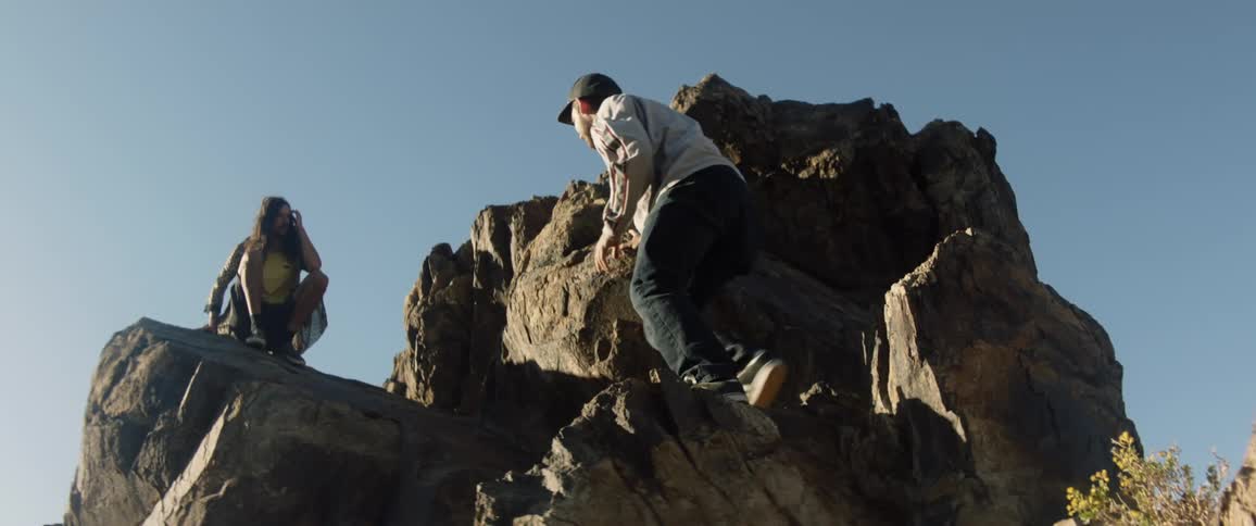A man climbing up a rock towards a woman