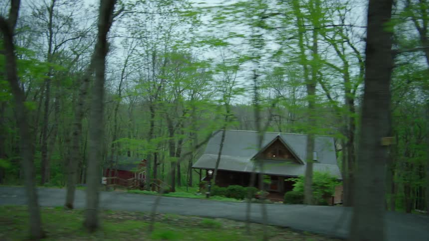 Rural homes in a woodland area as seen on an overcast day while passing by in a vehicle