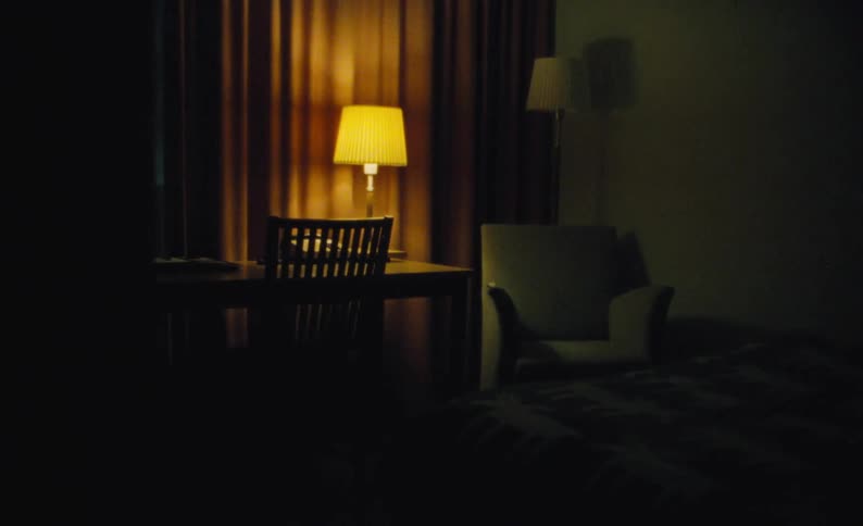 A table lamp glowing in a dark bedroom at night