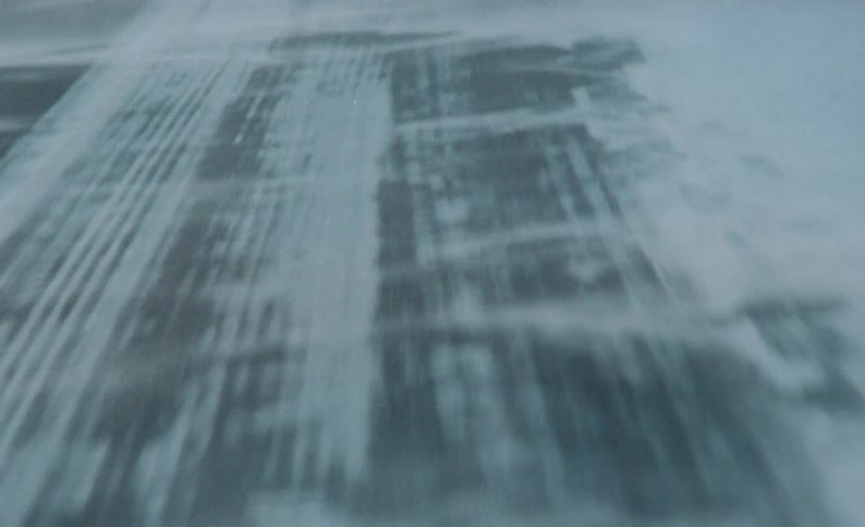 A salt and snow covered road that has blowing snow across it