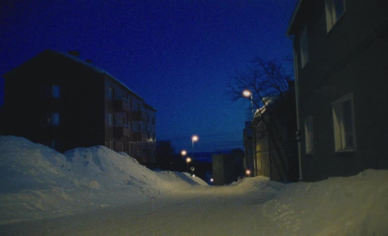 A snowy street through a residential area at night