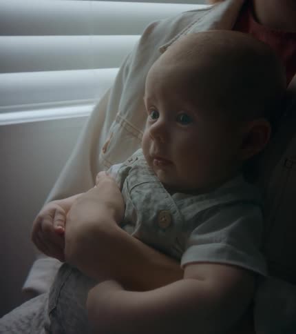 A baby sitting in an adults arms smiling