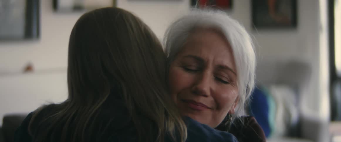 A woman kissing another woman on the cheek while hugging her