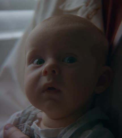 Close up of the face of a baby looking at a person outside the frame