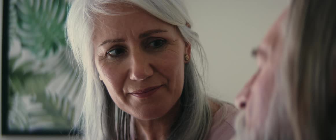 Woman with gray hair looks at elderly man with affection