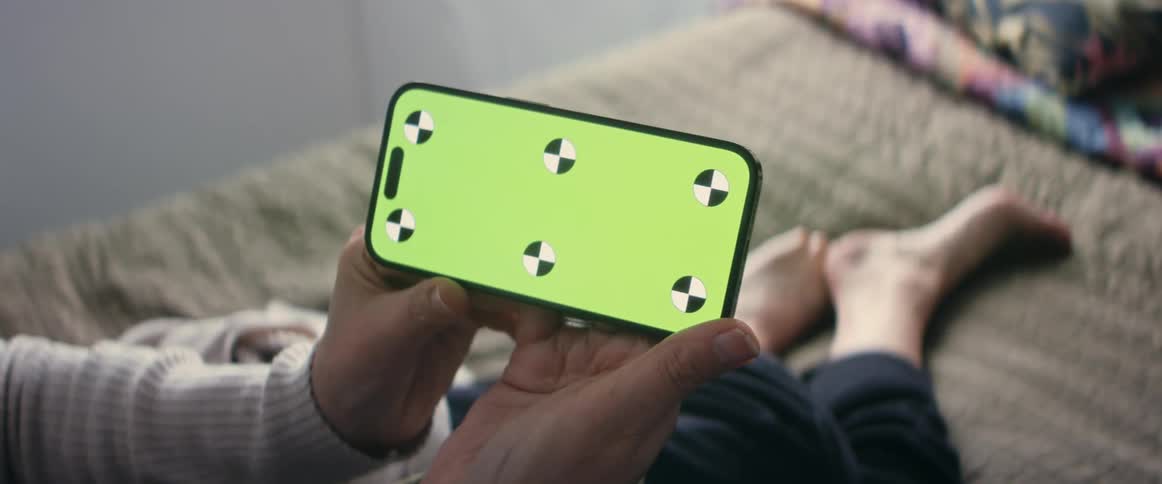A person is holding a smart phone and sitting indoors