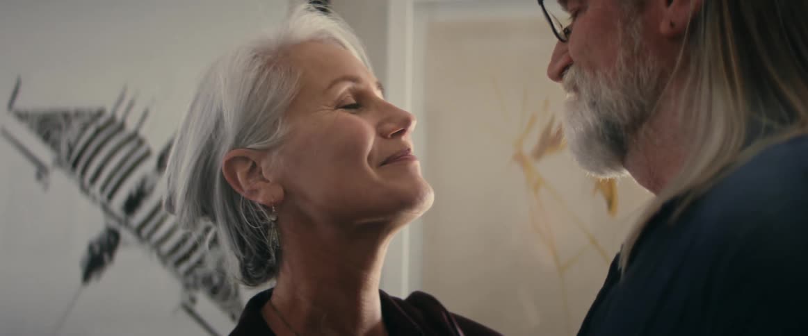Older couple kiss then lean their foreheads together while slow dancing