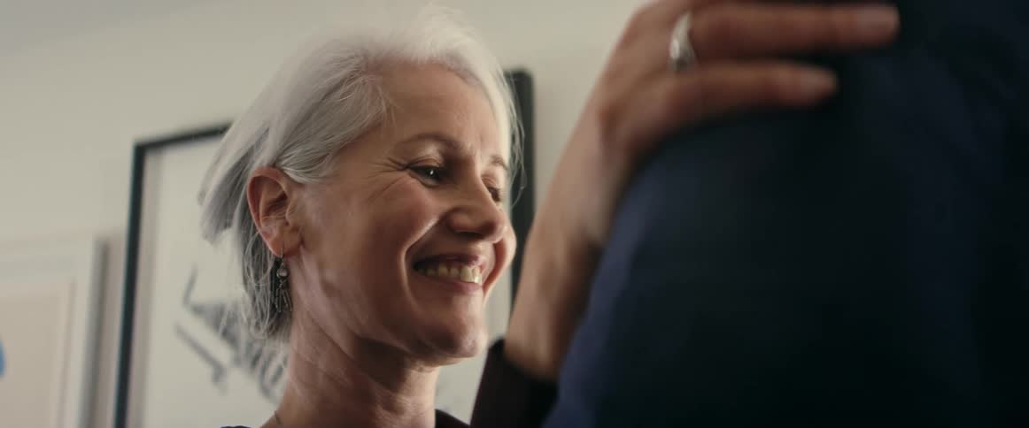 Two elderly people dancing in a room