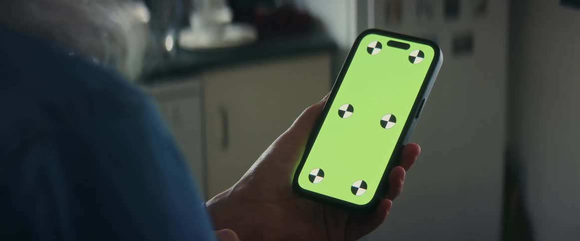 Elderly man uses mobile phone in the kitchen