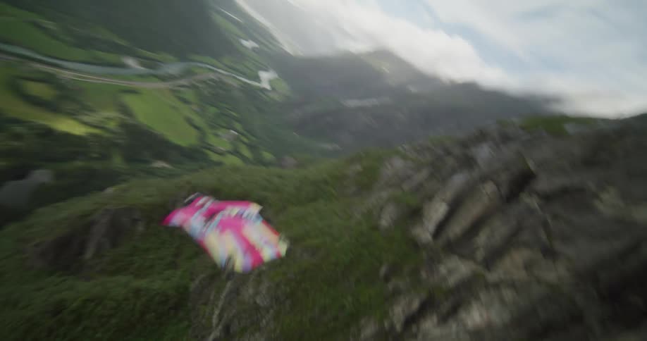 A person gliding through a green grassy valley