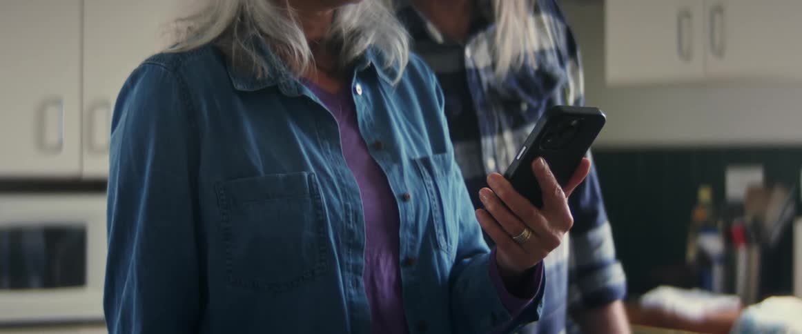 Man and woman are standing in a kitchen and looking at a phone