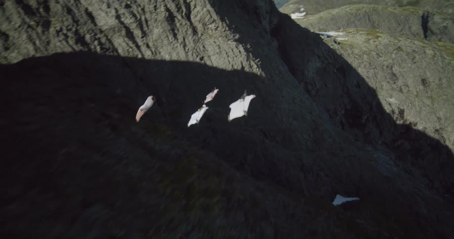 A group of people base jumping in suits