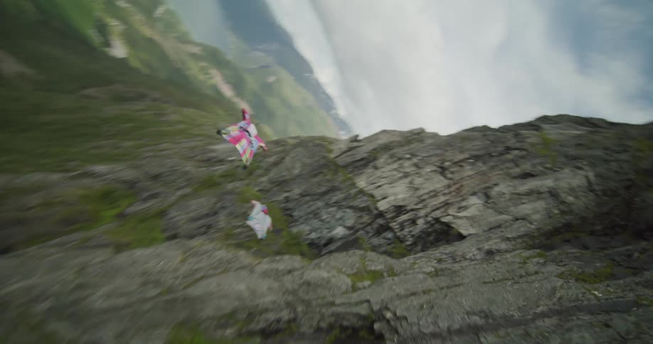 A view of people base jumping off a cliff