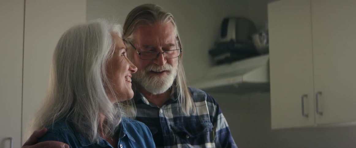 An elderly man and woman smiling while looking at a smartphone