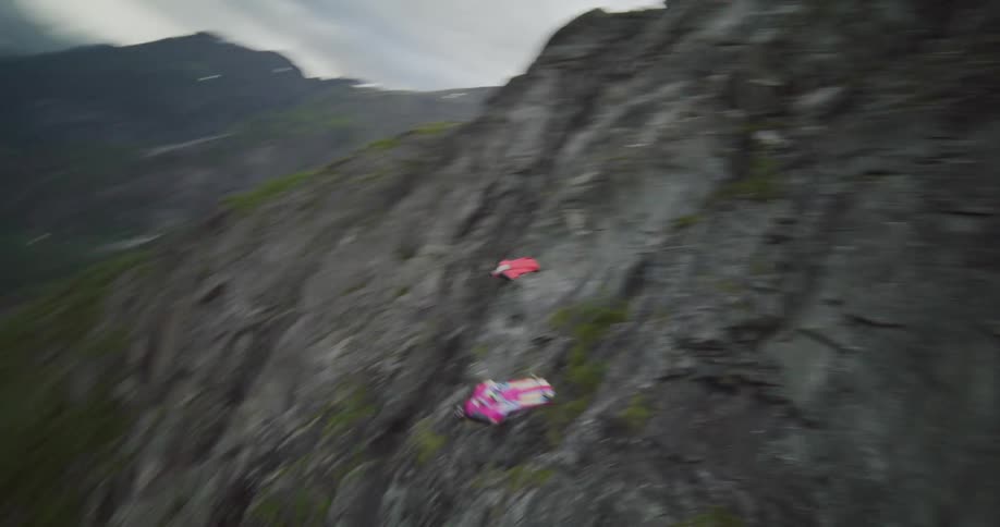 Two gliders jumping off a mountain edge and sailing down a valley