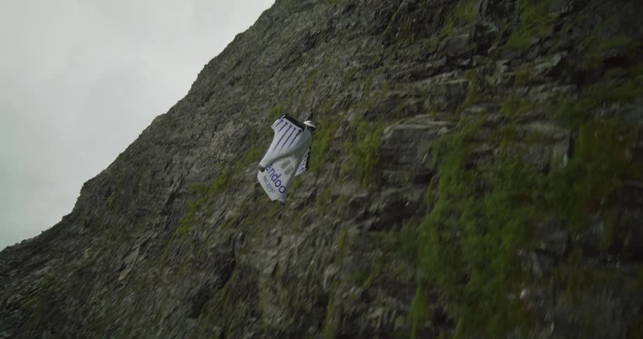 A person is wingsuit diving by the mountain