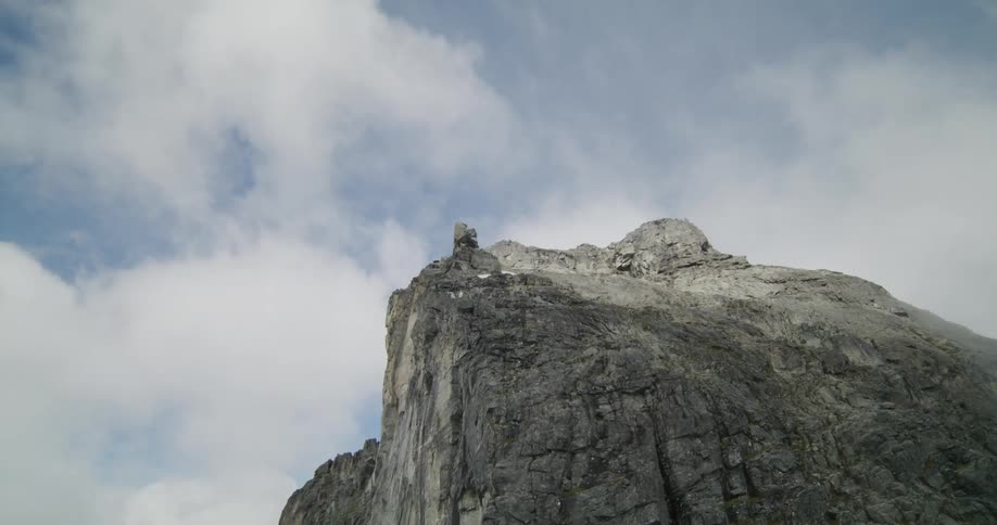 Skydiver jumps off cliff while others wait on a cloudy day