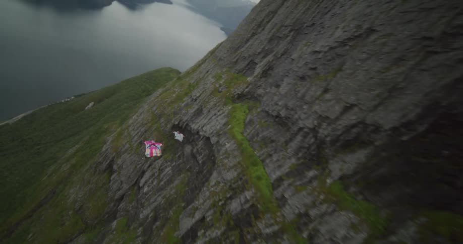 Two people gliding through the air and along a mountain range