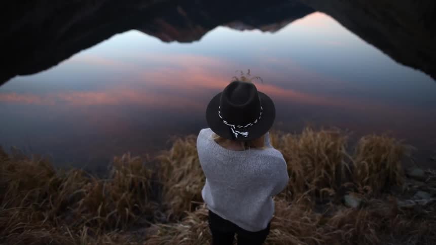 A woman is standing by the the water
