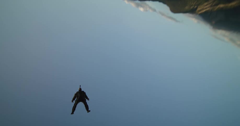 Wingsuit flier flies over field and deploy parachute