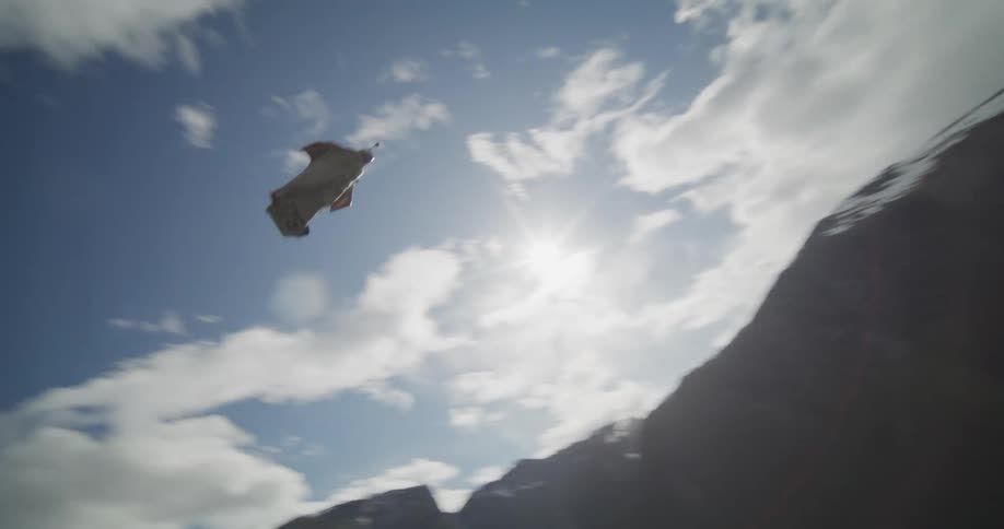 A glider flying through the air above water and vegetation