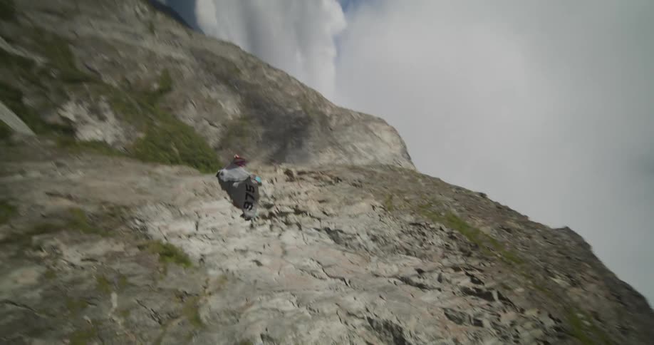 A view of a person diving off a cliff in a wing suit