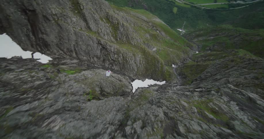 A person jumping off a mountain cliff in a wingsuit and gliding over the terrain