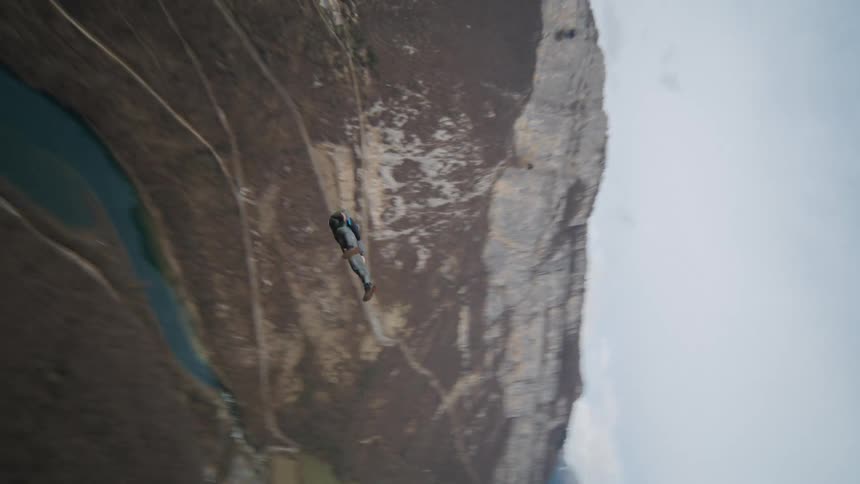 A man in a wing suit flies over a steep canyon
