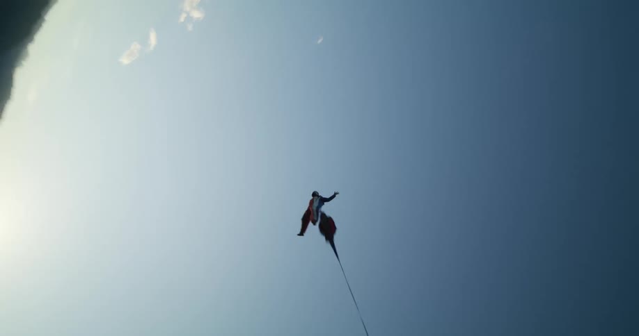 A person wingsuit flying and deploying a parachute over mountains