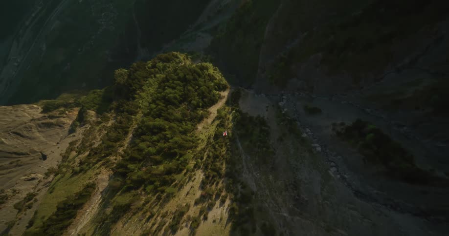 A person wingsuit flying off a mountain cliff
