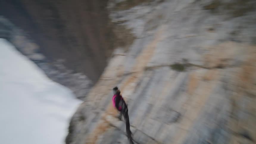 A person jumps off a cliff and then releases a parachute