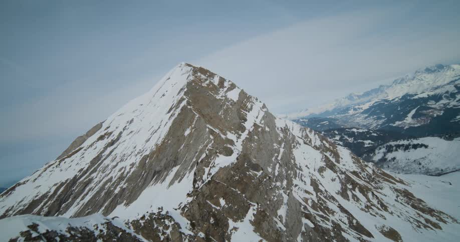 A panning shot of a mountain range with snow capped tips