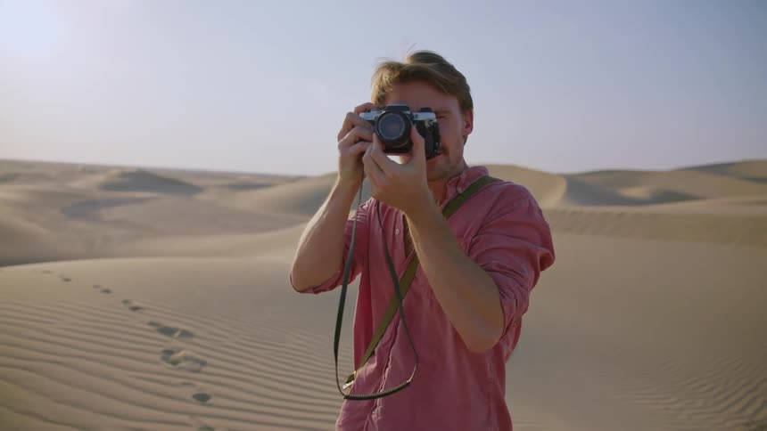 A man is taking pictures in the desert