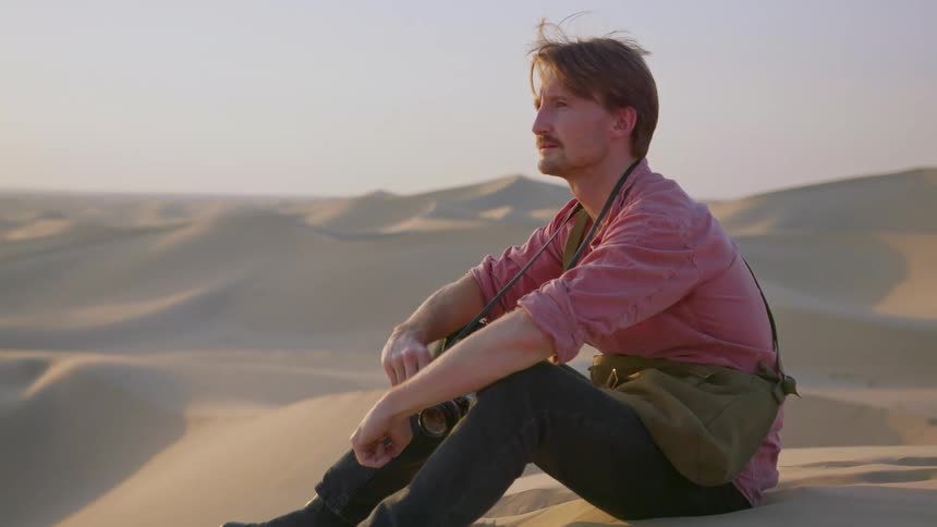 Man sitting on the sand in a barren hilly area