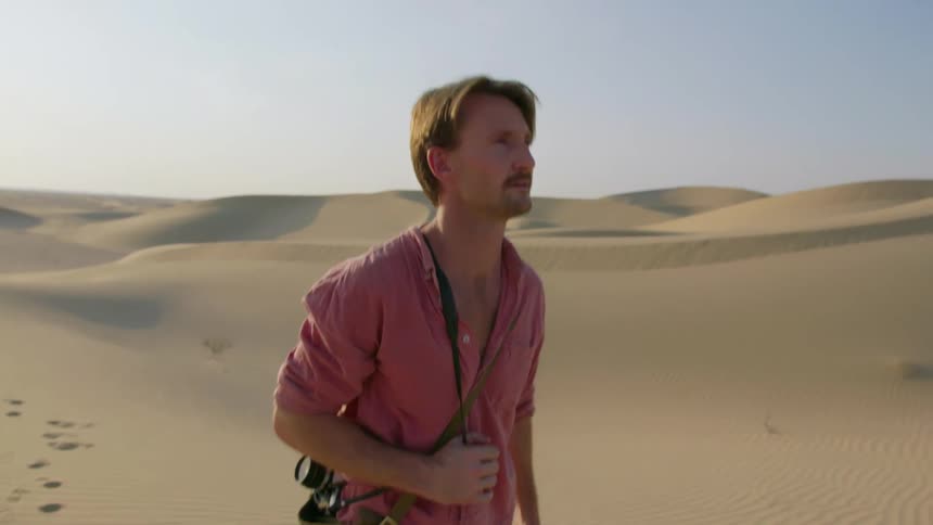 A photographer walks in the desert