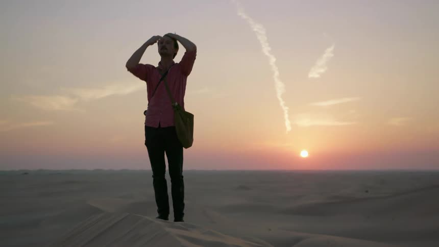 A man is hiking in sand dunes at dusk