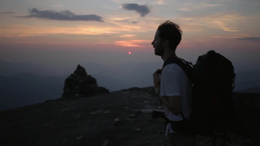 Hiker standing atop a mountain at sunset