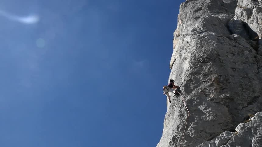 A person is rock climbing on a sunny day