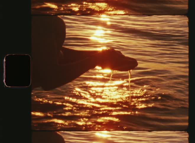 Close-up of a woman crouched and putting her hands in ocean waves at sunset enjoying the connection to Mother Nature through the wet element while feeling the refreshment of the fresh and moving water