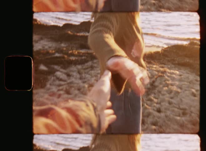 Retro POV shot of a pretty girl that grabs the hand of a man and turns around to start walking towards the water and into the last sunlight during romantic date on a warm summer evening as the young couple in love enjoys the sunset