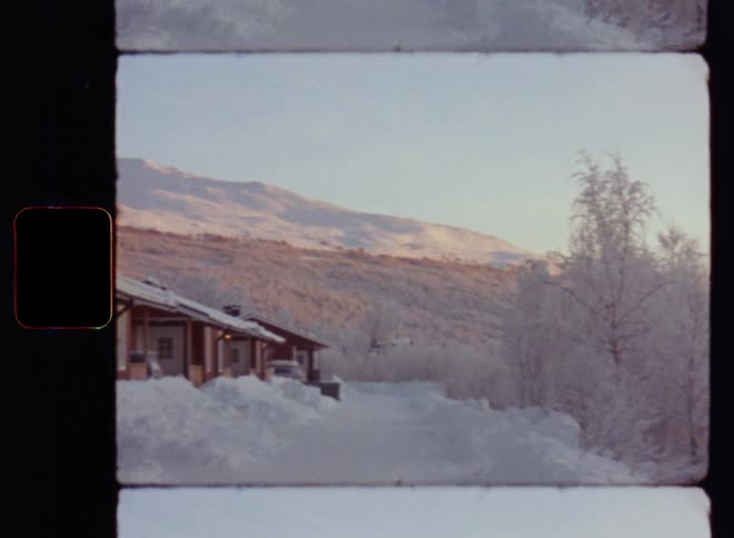 Ws pan across snowy mountainous region with ranch style sidebyside winter vacation cabins as small holiday homes or houses in a ski resort offering winter trips and holidays on the snow covered countryside with frozen roads and icy trees