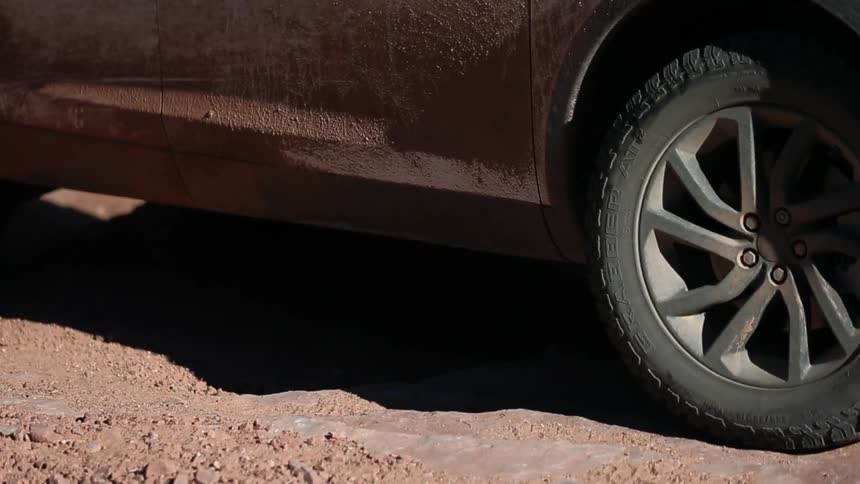 A car spins it's tires traveling over dirt and rocks