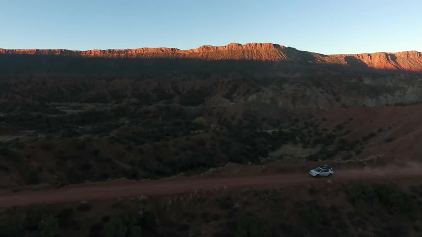 Vehicle moving along a dirt road in a barren area